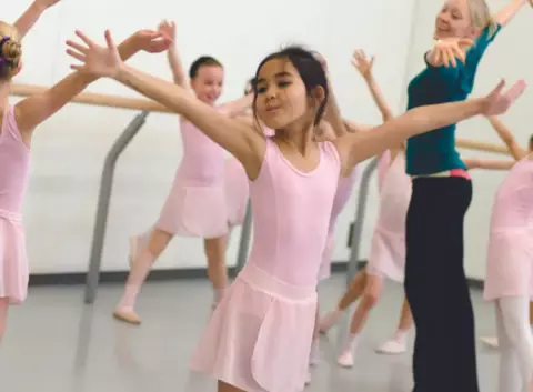 Une jeune danseuse étirant les bras dans un cours de danse